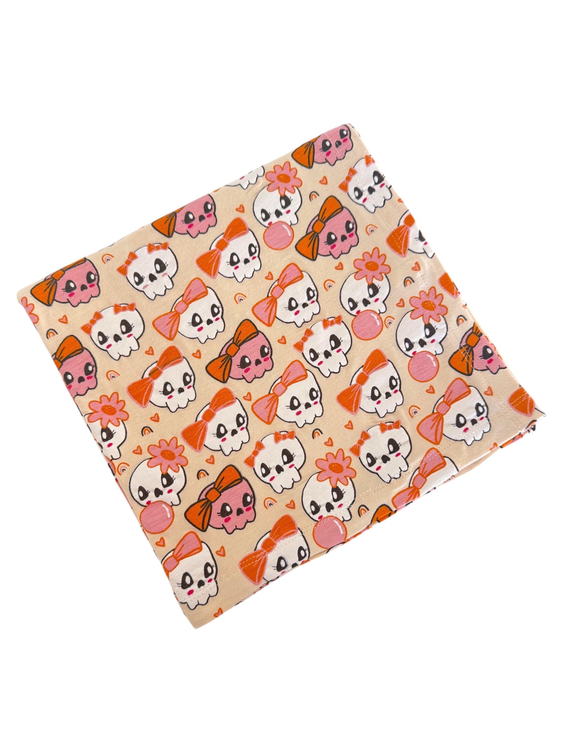 Colorful fabric featuring cartoon skulls with bows and flowers on a light background. Perfect for crafts or apparel.