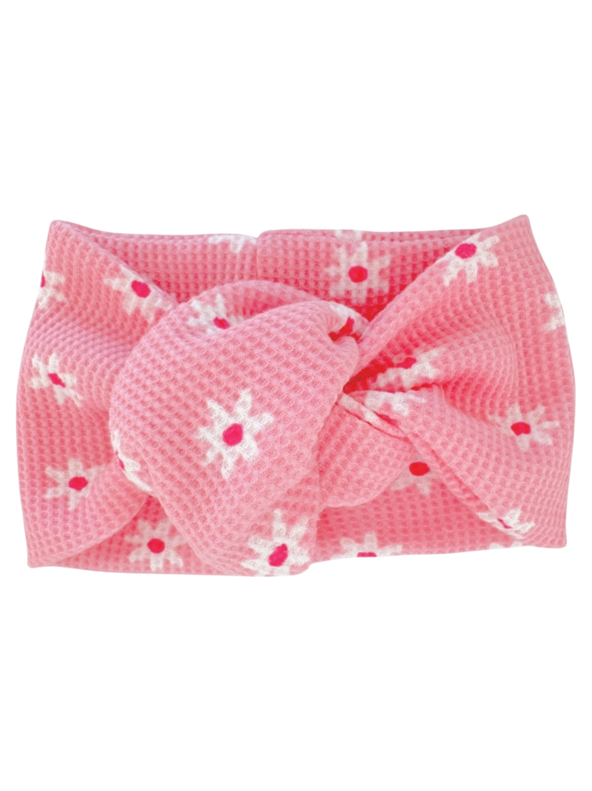Pink headband with a knot design and white flowers with red centers on a textured fabric.