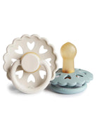 Two baby pacifiers with heart-shaped designs, one in pale beige and the other in light blue.