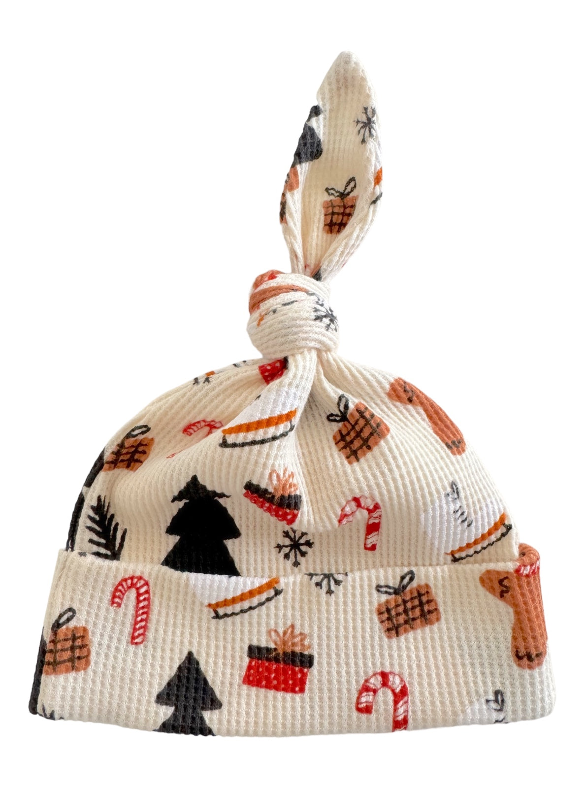 Knotted baby hat with festive patterns including trees, gifts, and candy canes on a white background.