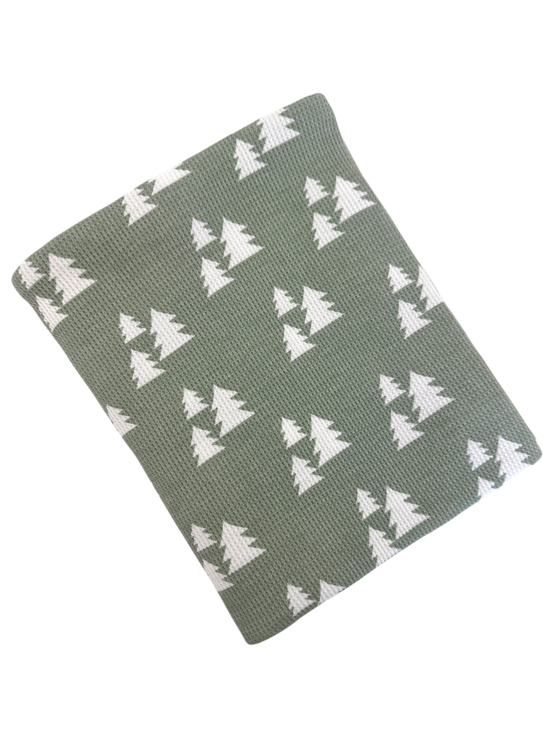Green blanket with white tree pattern, perfect for cozying up in a rustic or nature-themed decor.