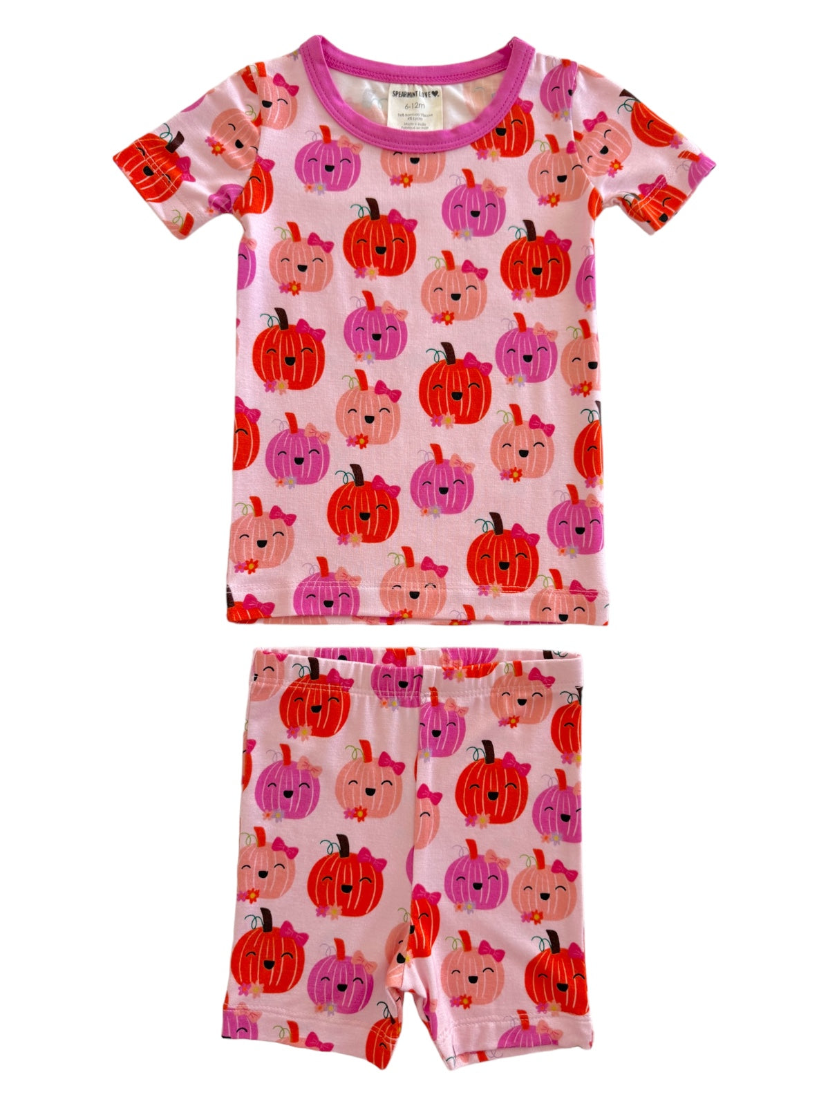 Child's pink pajamas with colorful pumpkin patterns, featuring a short-sleeve top and shorts. Perfect for fall!