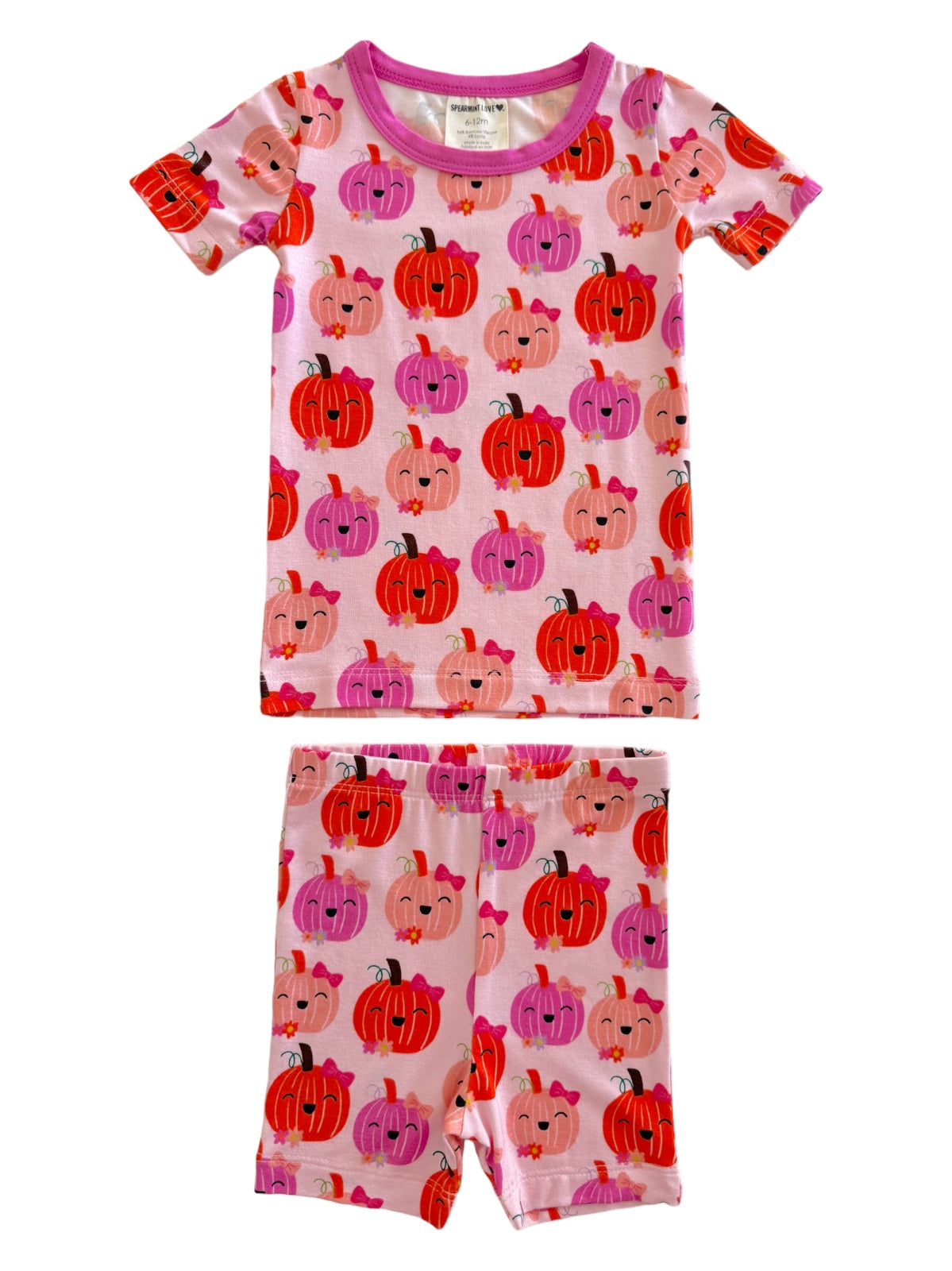 Child's pink pajamas with colorful pumpkin patterns, featuring a short-sleeve top and shorts. Perfect for fall!