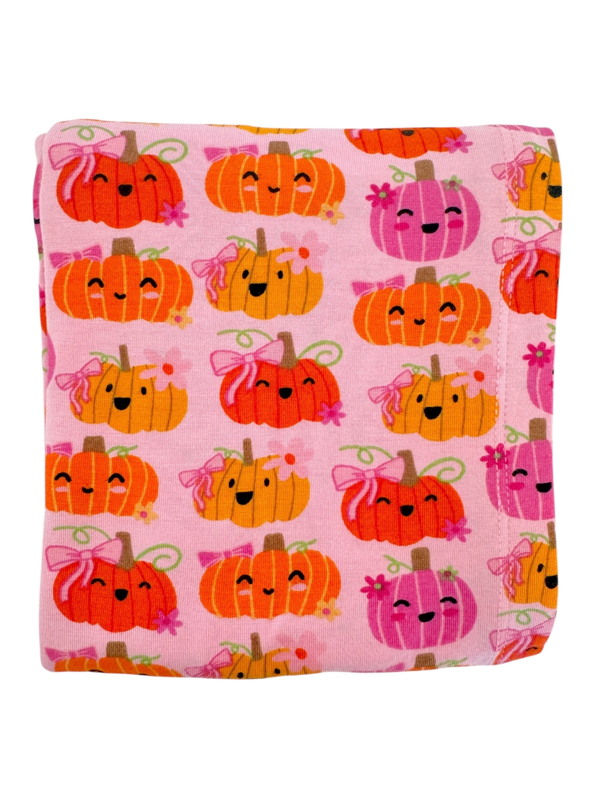 Pink blanket featuring cute, smiling pumpkins in orange and pink with bows and floral designs.