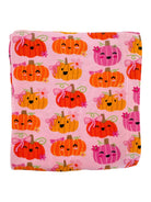 Pink blanket featuring cute, smiling pumpkins in orange and pink with bows and floral designs.