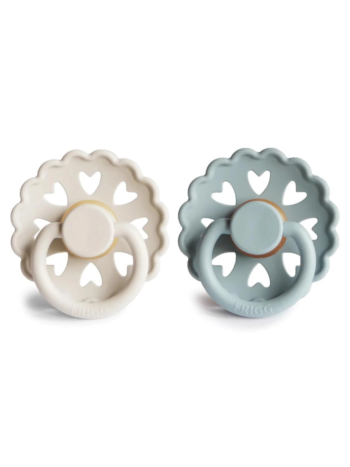 Two silicone pacifiers in white and blue with heart cutouts, designed for babies. Brand: Frigg.
