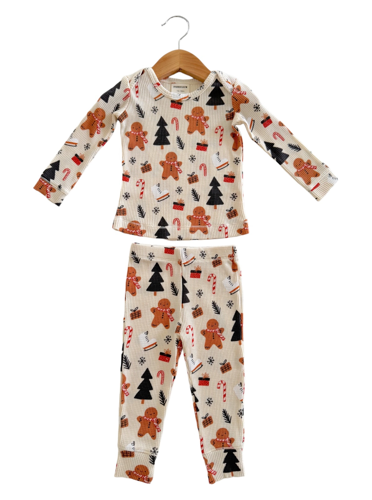 Children's holiday pajamas featuring gingerbread men, Christmas trees, and candy canes in a playful design.