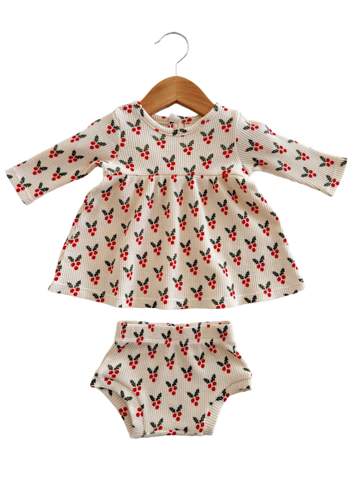 Girls' dress and matching bloomers with a floral pattern, hanging on a wooden hanger.