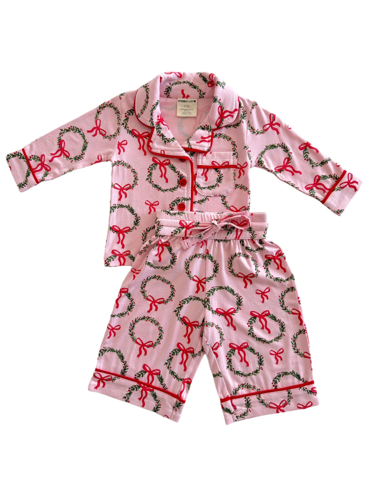 Pink pajama set featuring green wreaths and red bows, designed for infants or toddlers.