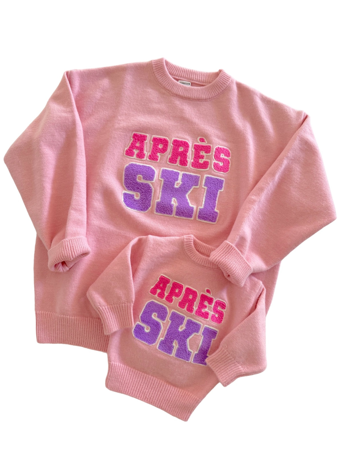 Matching pink sweaters with "APRÈS SKI" graphic, one adult size and one child size.