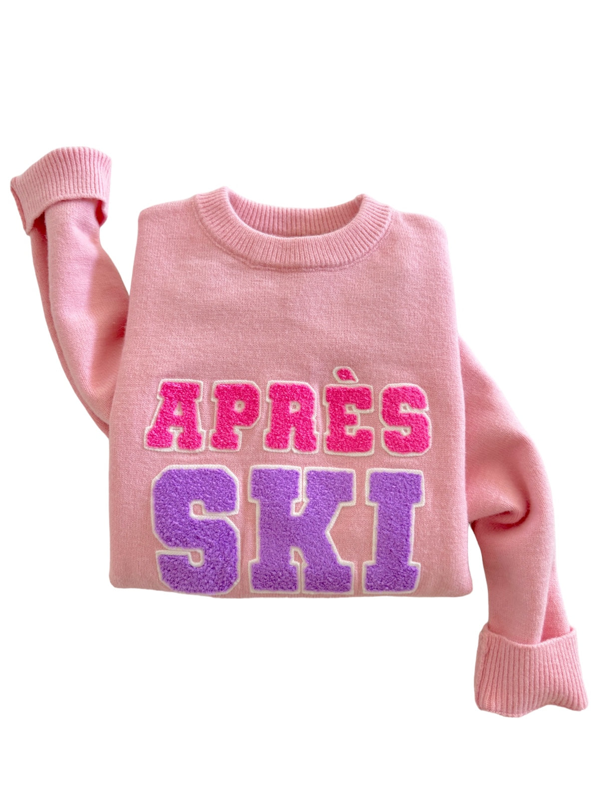 Pink sweater featuring bold, textured "APRES SKI" lettering in purple and pink hues.