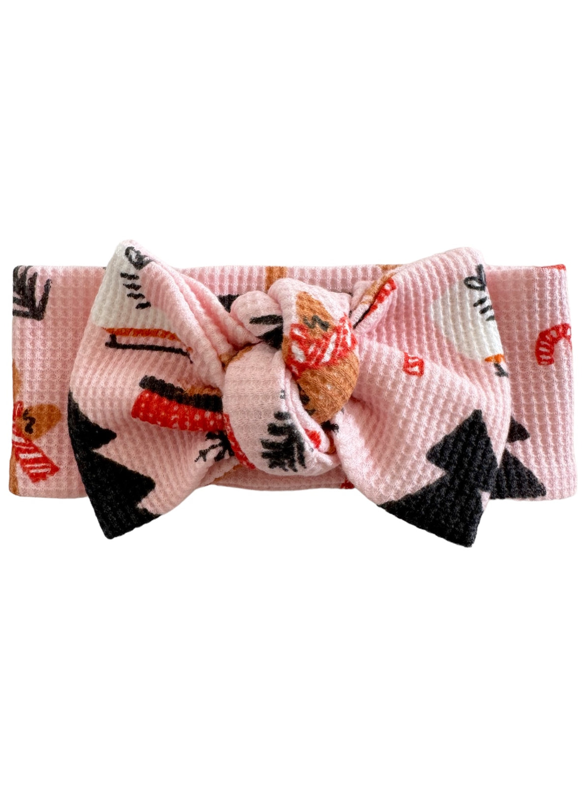 Pink bow headband with whimsical patterns of trees and holiday treats. Ideal for kids' fashion accessories.