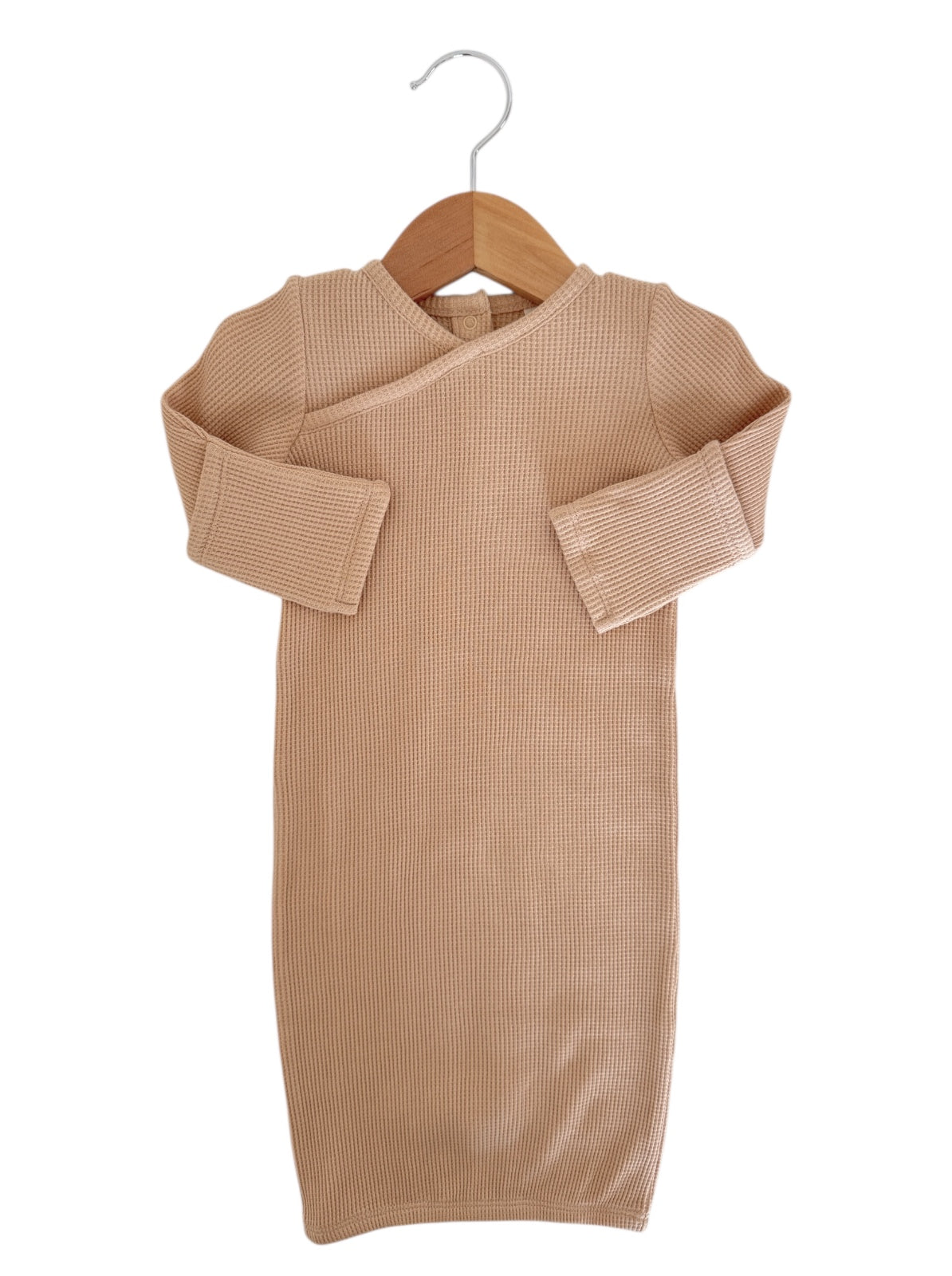 Beige, long-sleeve, ribbed baby dress hanging on a wooden hanger against a white background.