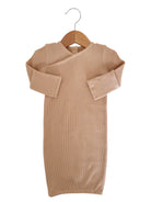 Beige, long-sleeve, ribbed baby dress hanging on a wooden hanger against a white background.