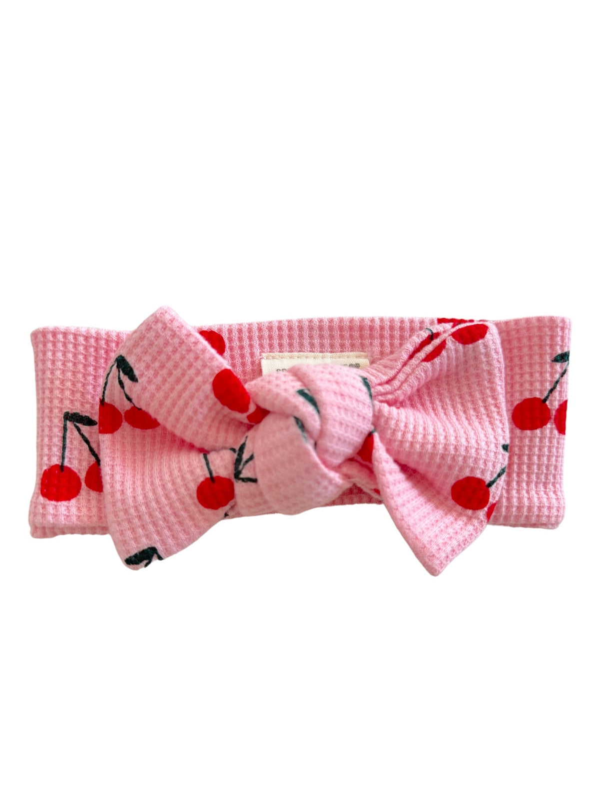 Pink headband with a large bow, featuring a cherry pattern throughout.