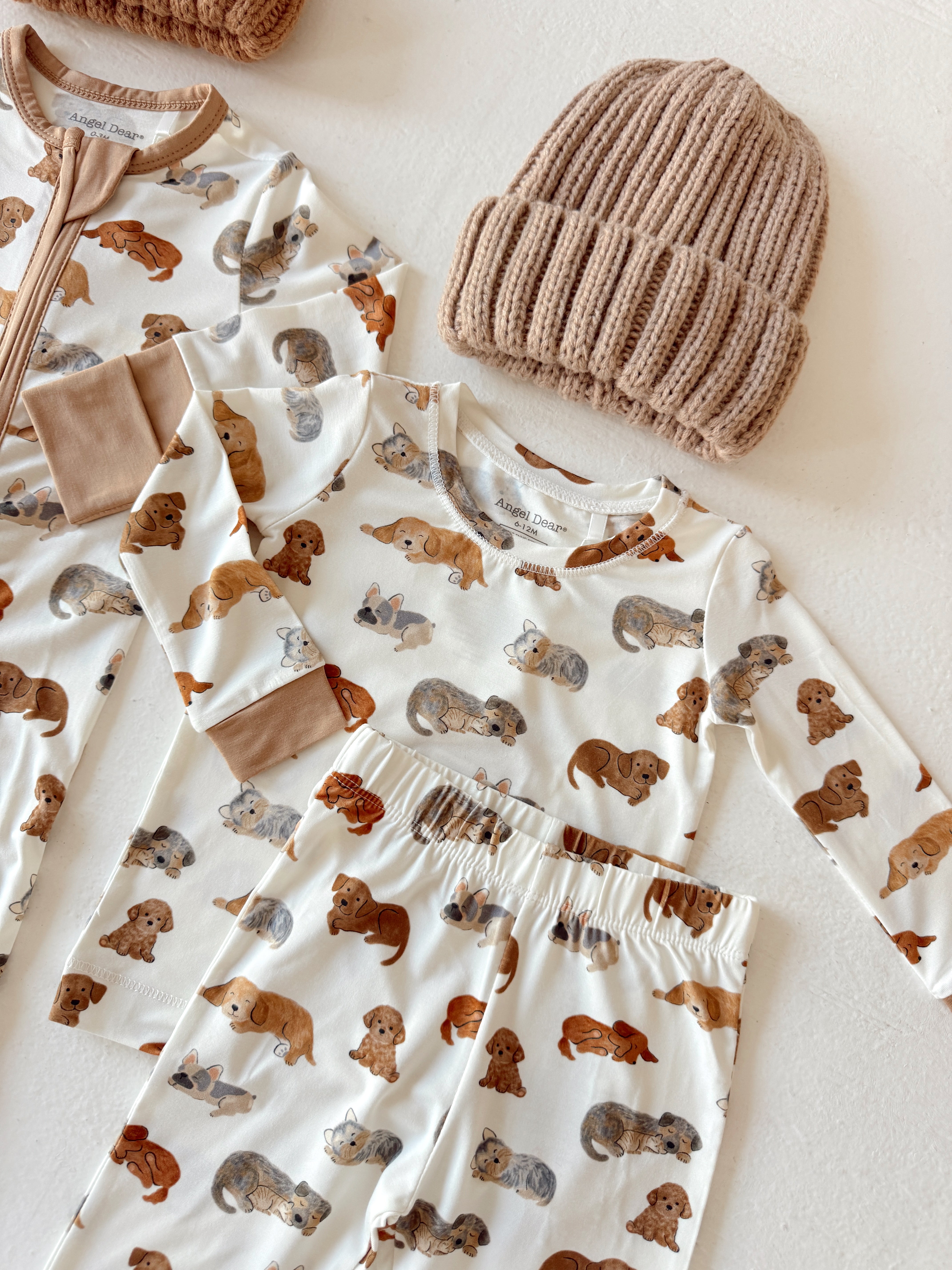 Child's pajamas and hat featuring playful dog patterns in earthy tones on a light background.