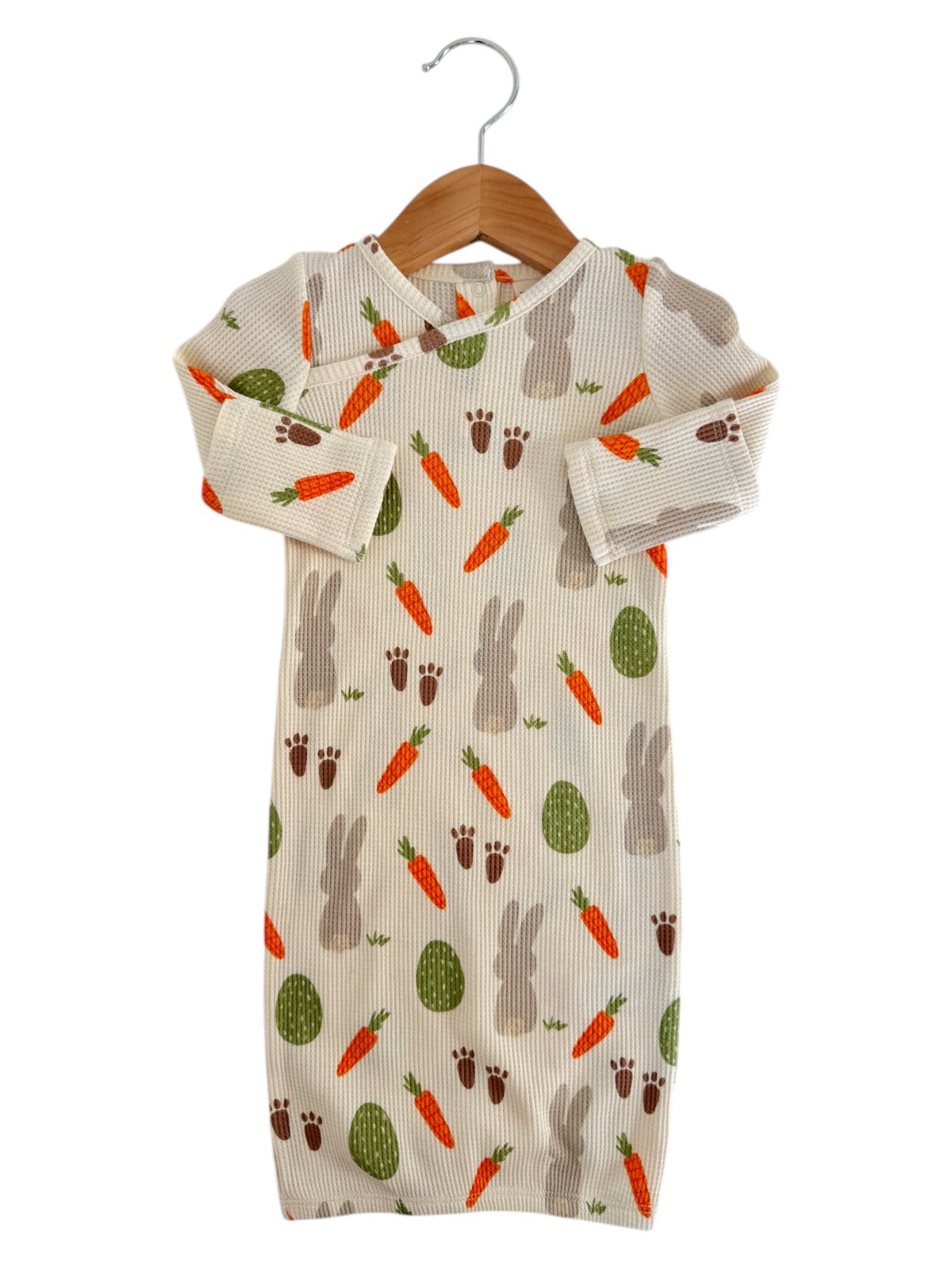 Cute baby sleeper with bunny and carrot print, hanging on a wooden hanger against a white background.