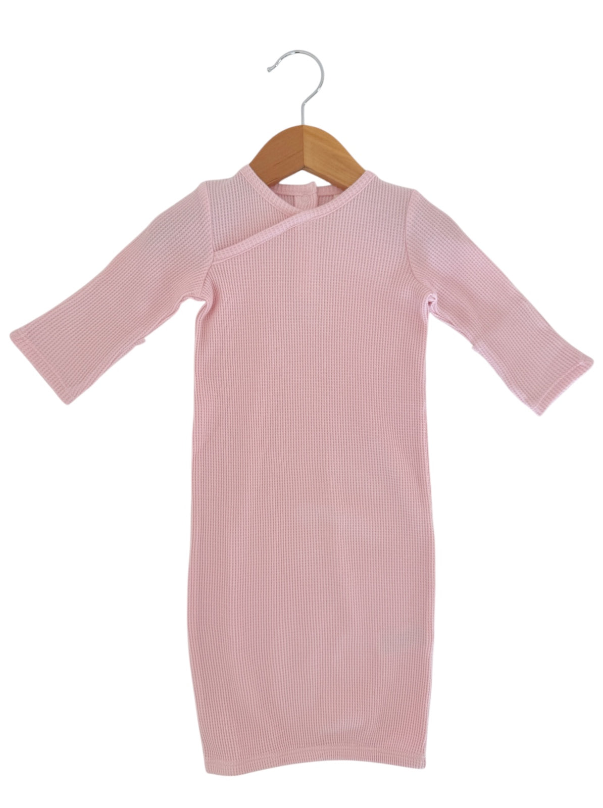 Pale pink ribbed dress with long sleeves hanging on a wooden hanger against a white background.