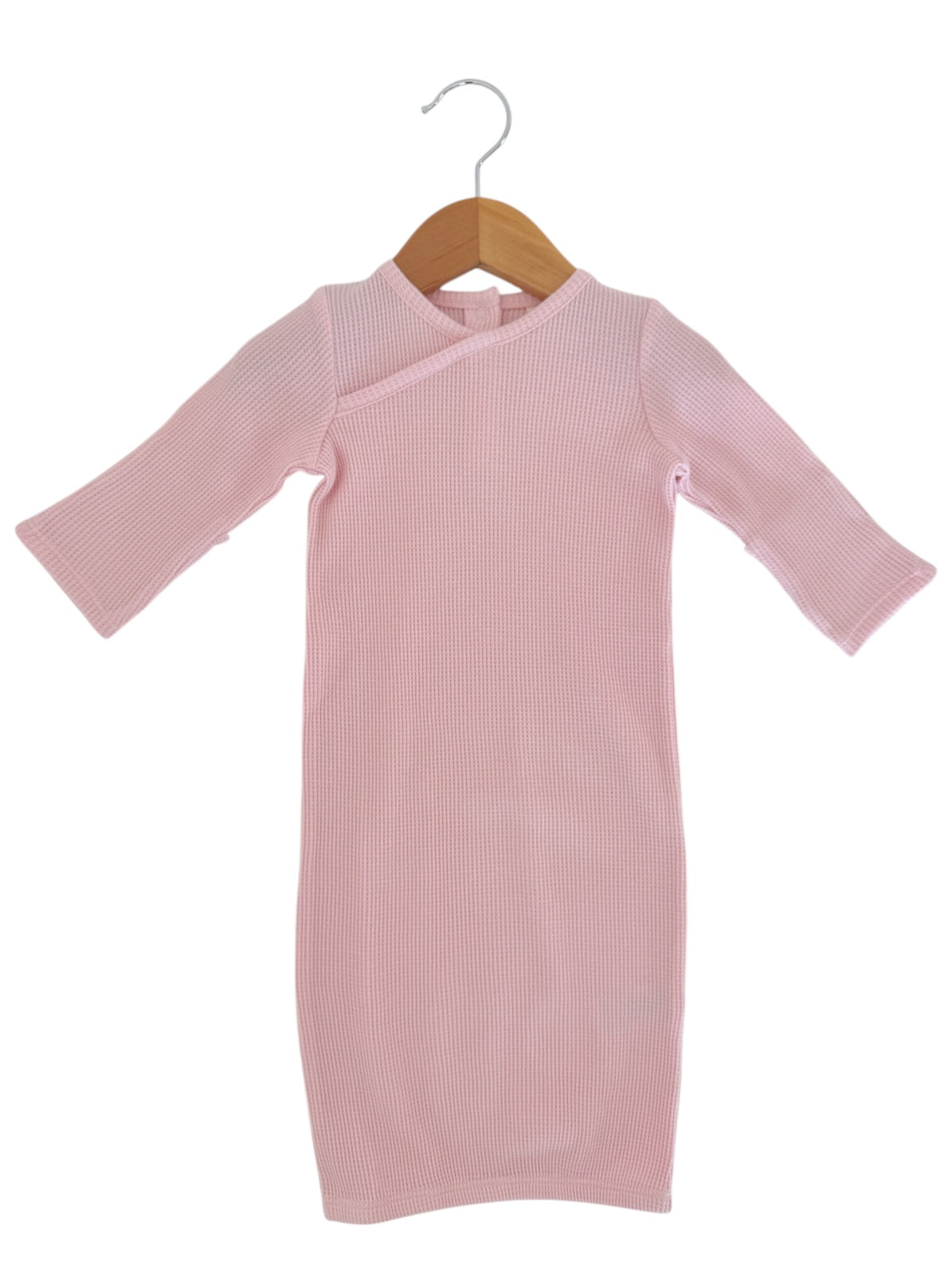 Pale pink ribbed dress with long sleeves hanging on a wooden hanger against a white background.
