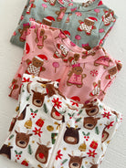 Three festive children's pajamas featuring gingerbread and reindeer patterns in holiday colors.