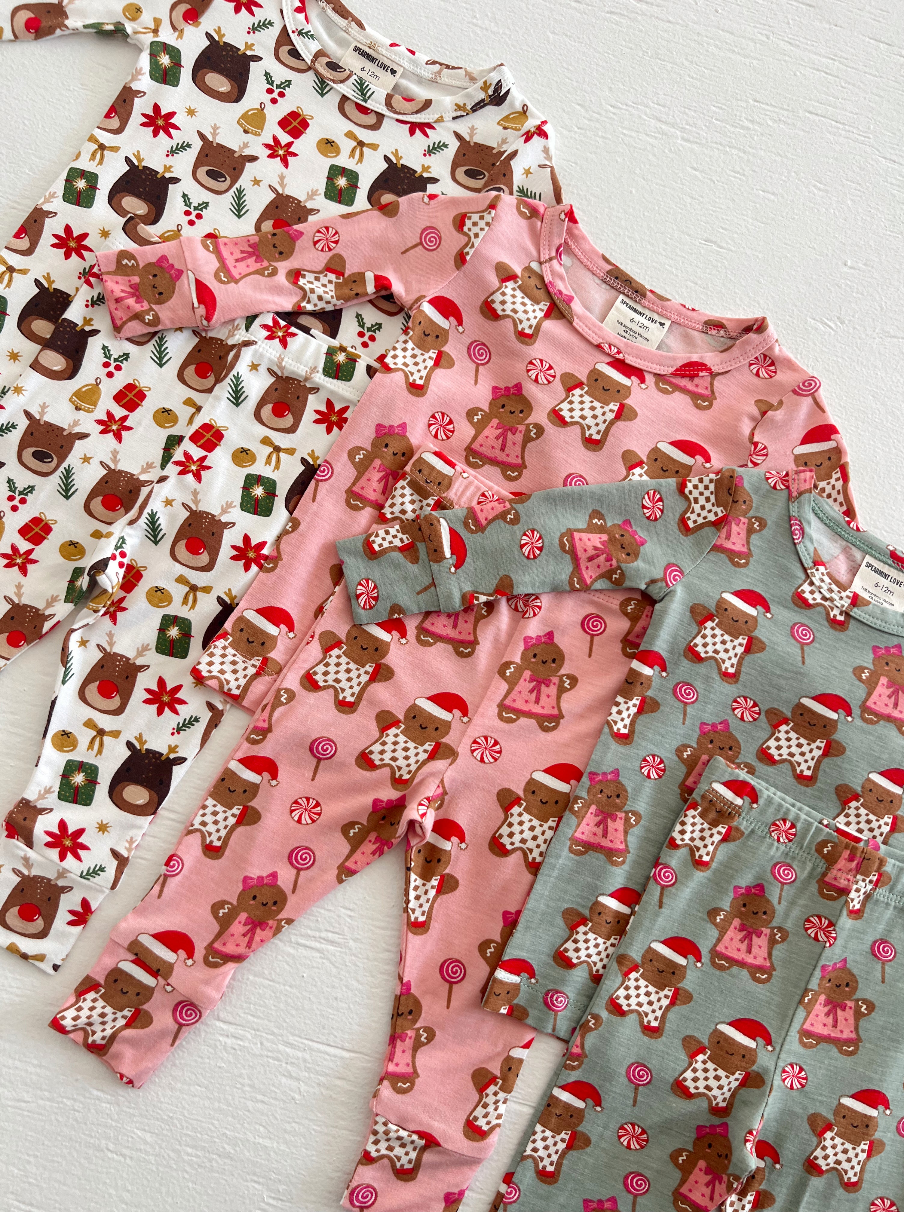 Four pairs of festive children's pajamas featuring reindeer and gingerbread designs in playful colors.