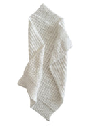 Textured white towel draped elegantly, showcasing a cozy and soft appearance for bathroom or kitchen use.