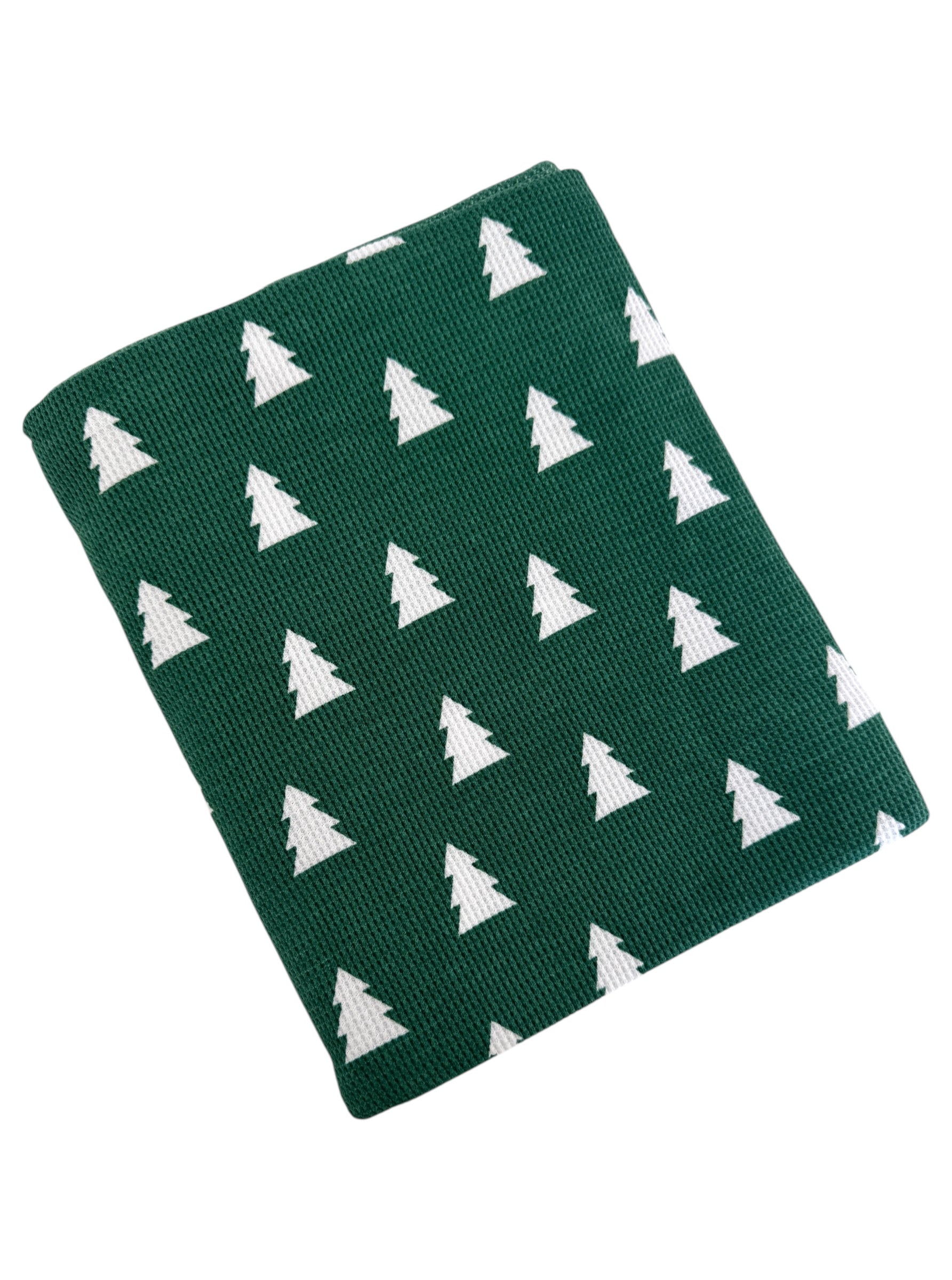Green blanket with white tree pattern, folded neatly for cozy holiday decoration.