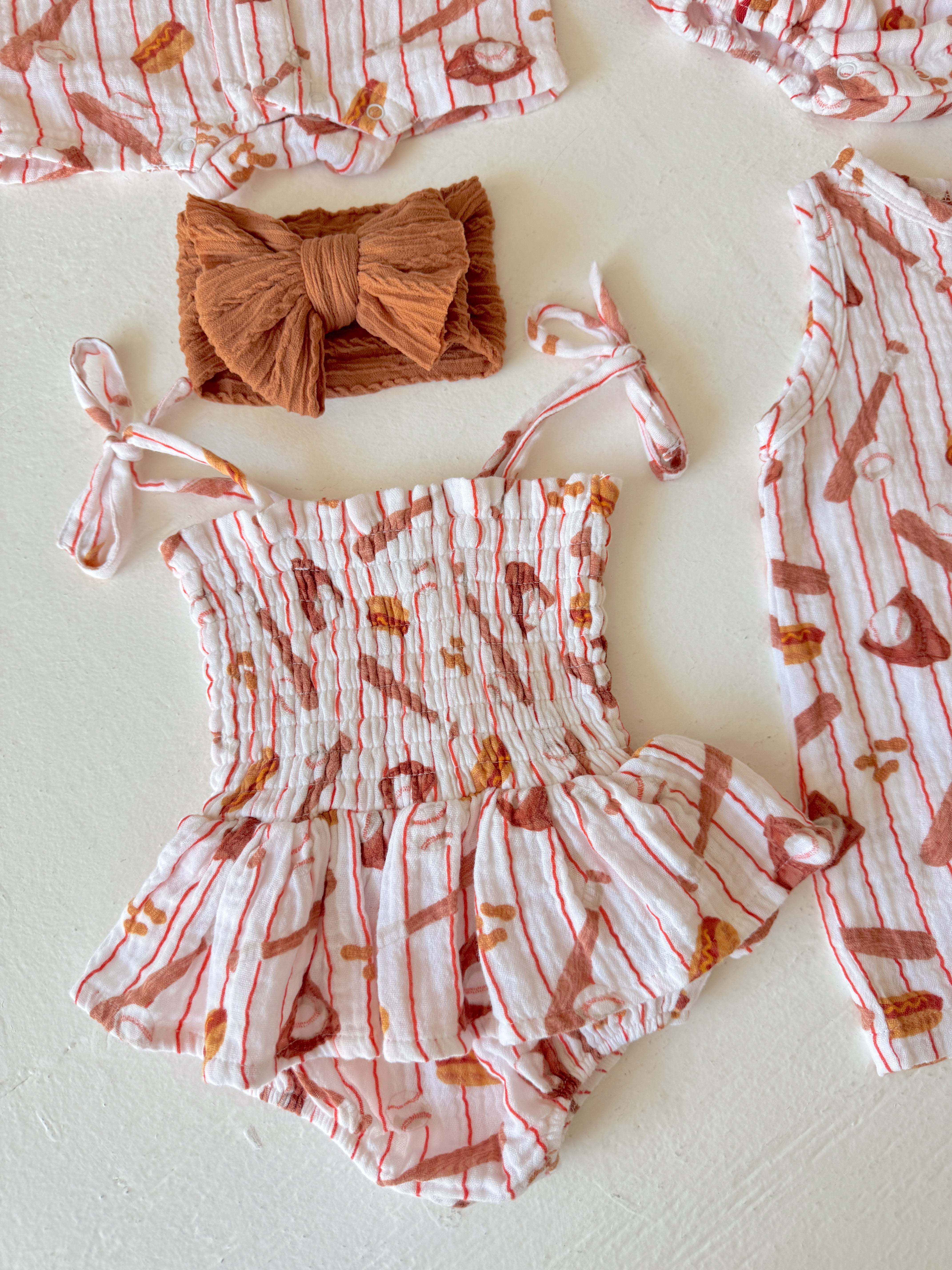 Baby clothing set featuring a pink and white striped romper with matching accessories.