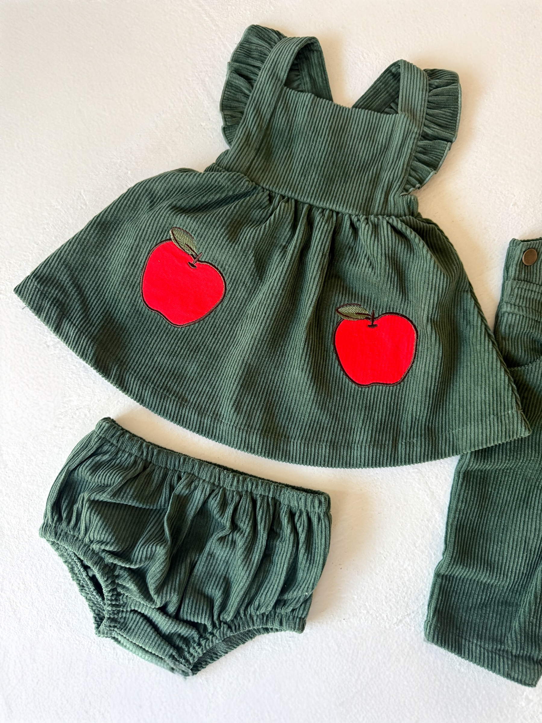 Green corduroy dress with red apple appliqués, paired with matching bloomer shorts.