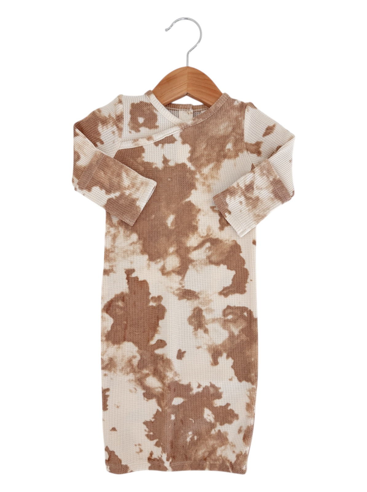 Brown and cream tie-dye dress hanging on a wooden hanger against a white background.