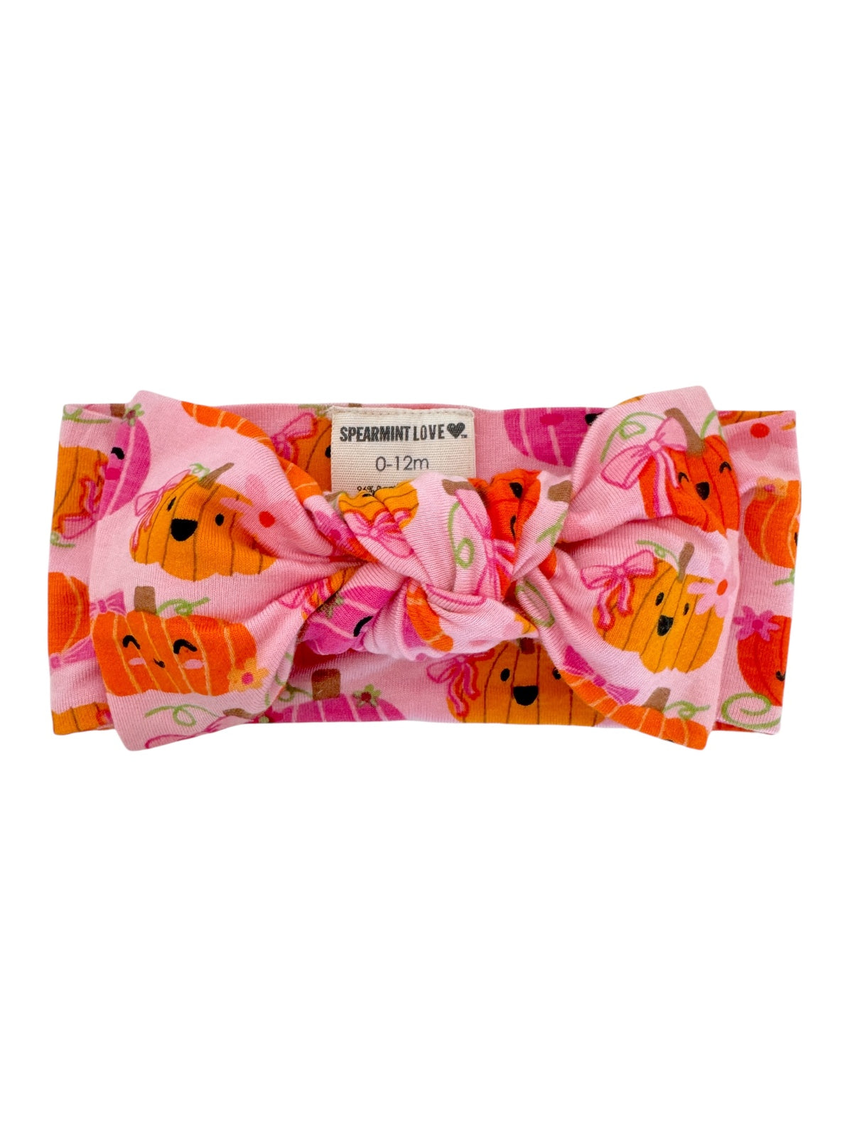 Pink headband with a large bow, featuring cheerful pumpkin prints, suitable for infants 0-12 months.