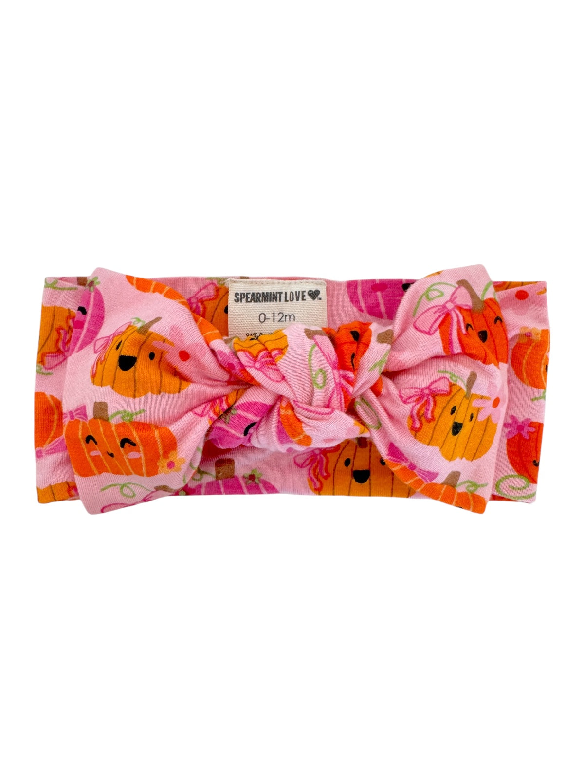 Pink headband with a large bow, featuring cheerful pumpkin prints, suitable for infants 0-12 months.