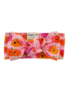 Pink headband with a large bow, featuring cheerful pumpkin prints, suitable for infants 0-12 months.