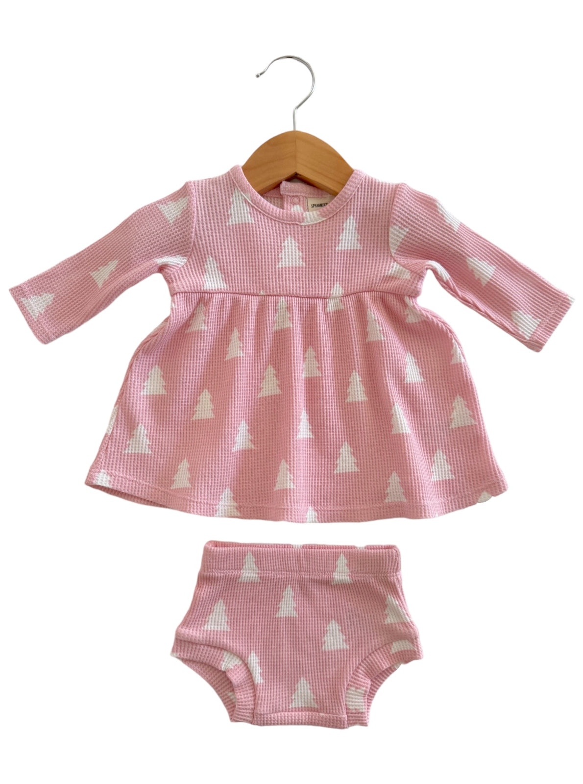 Pink children's dress with long sleeves and matching shorts, featuring white triangle patterns, displayed on a hanger.