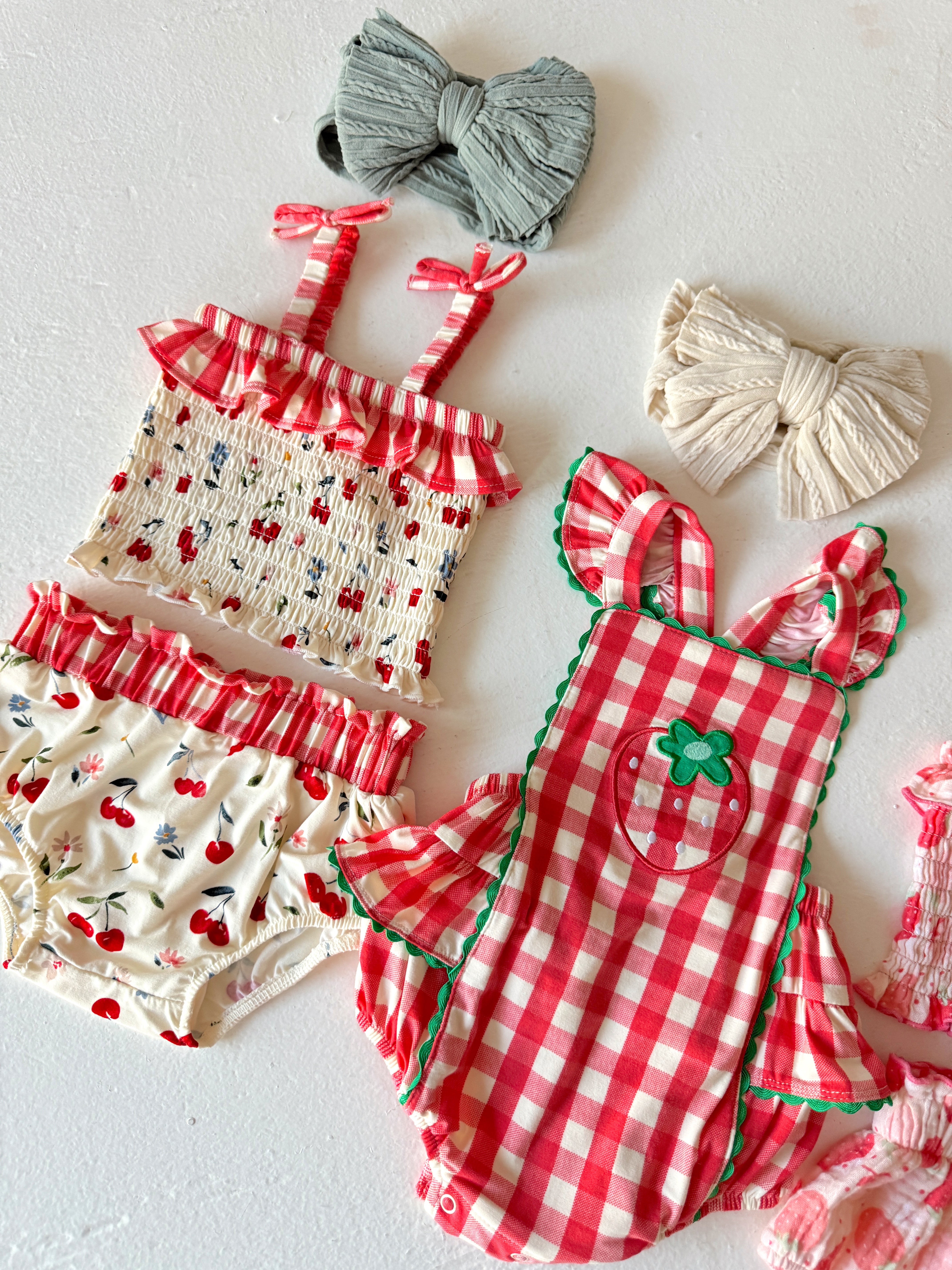 Assorted children's swimwear: two sets with ruffled detailing and hair bows in soft pastel colors.