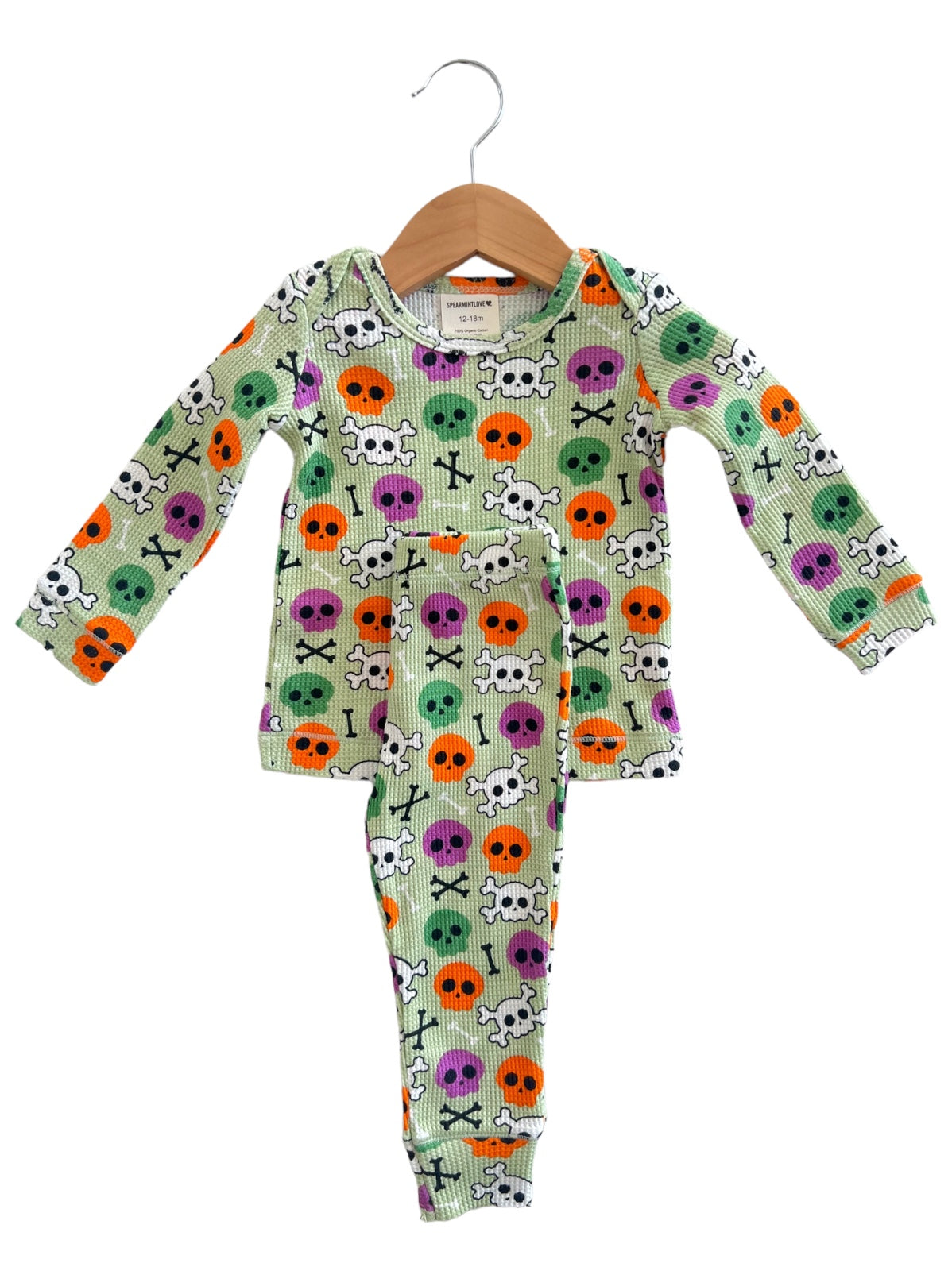 Colorful toddler pajama set with skull and crossbones design, featuring purple, orange, and green accents on a light background.