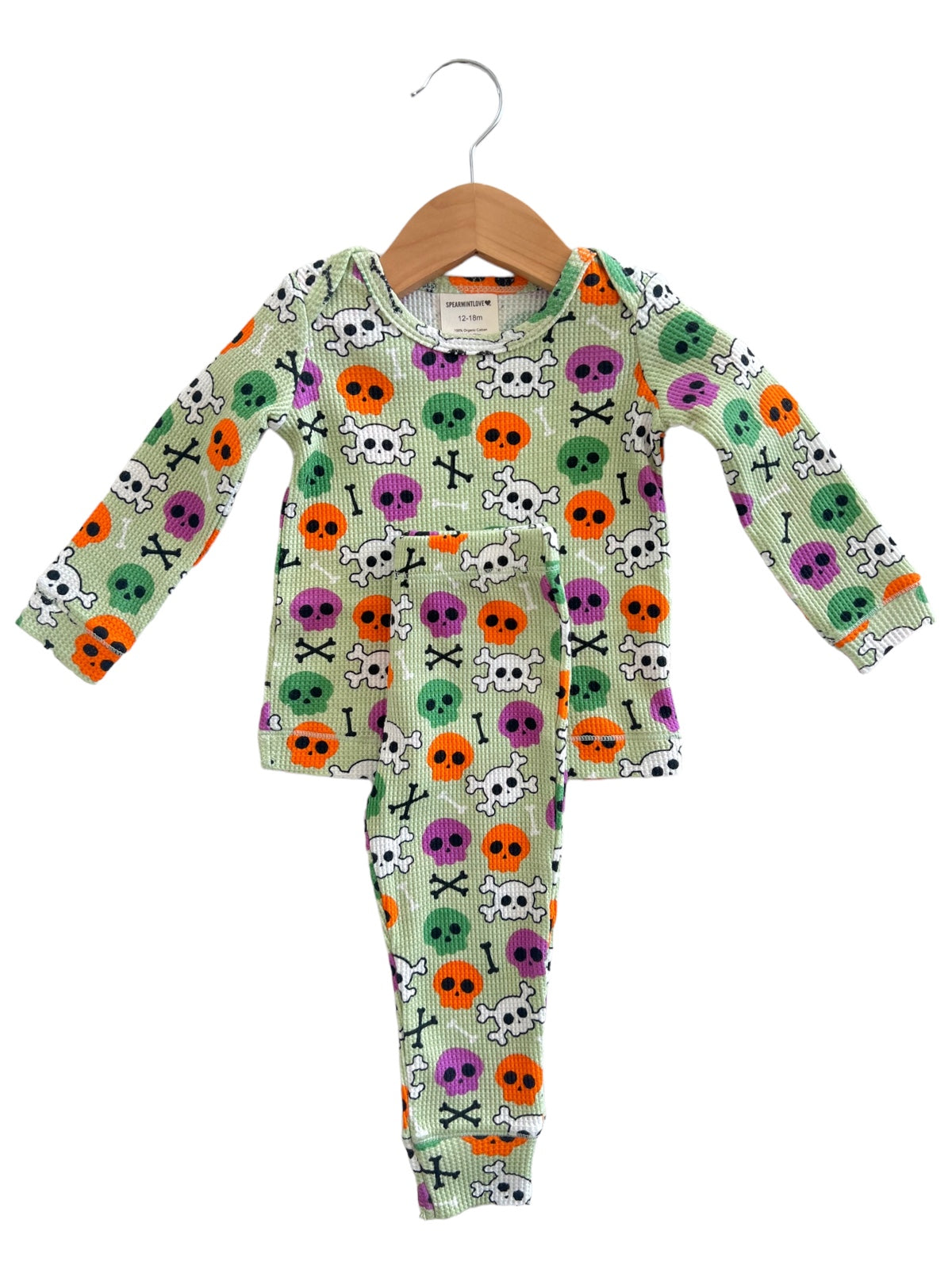 Colorful toddler pajama set with skull and crossbones design, featuring purple, orange, and green accents on a light background.