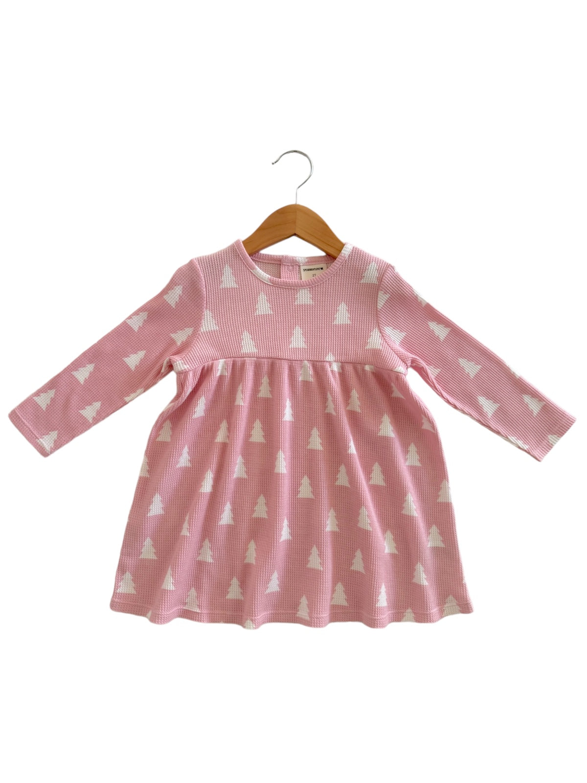 Pink long-sleeve dress with white tree pattern, displayed on a wooden hanger. Perfect for casual wear.