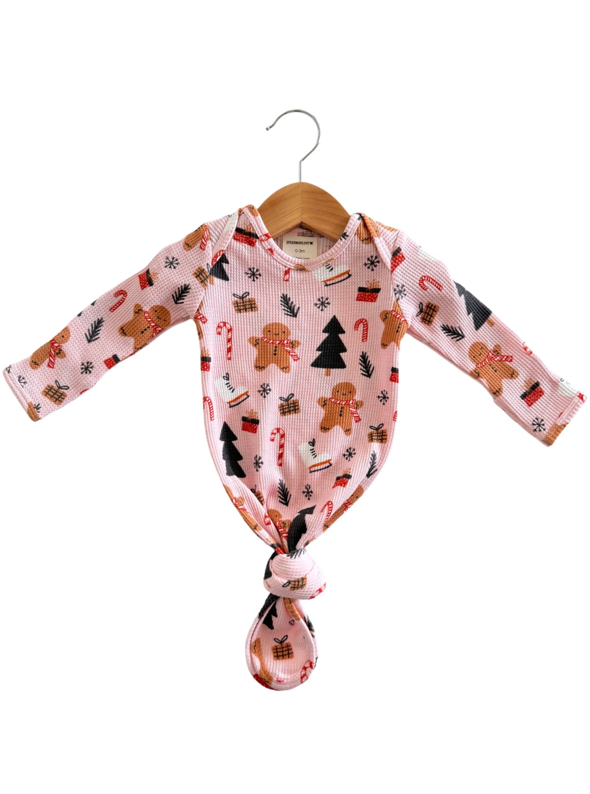 Pink baby onesie with gingerbread, candy canes, and Christmas trees, tied in a knot at the bottom.