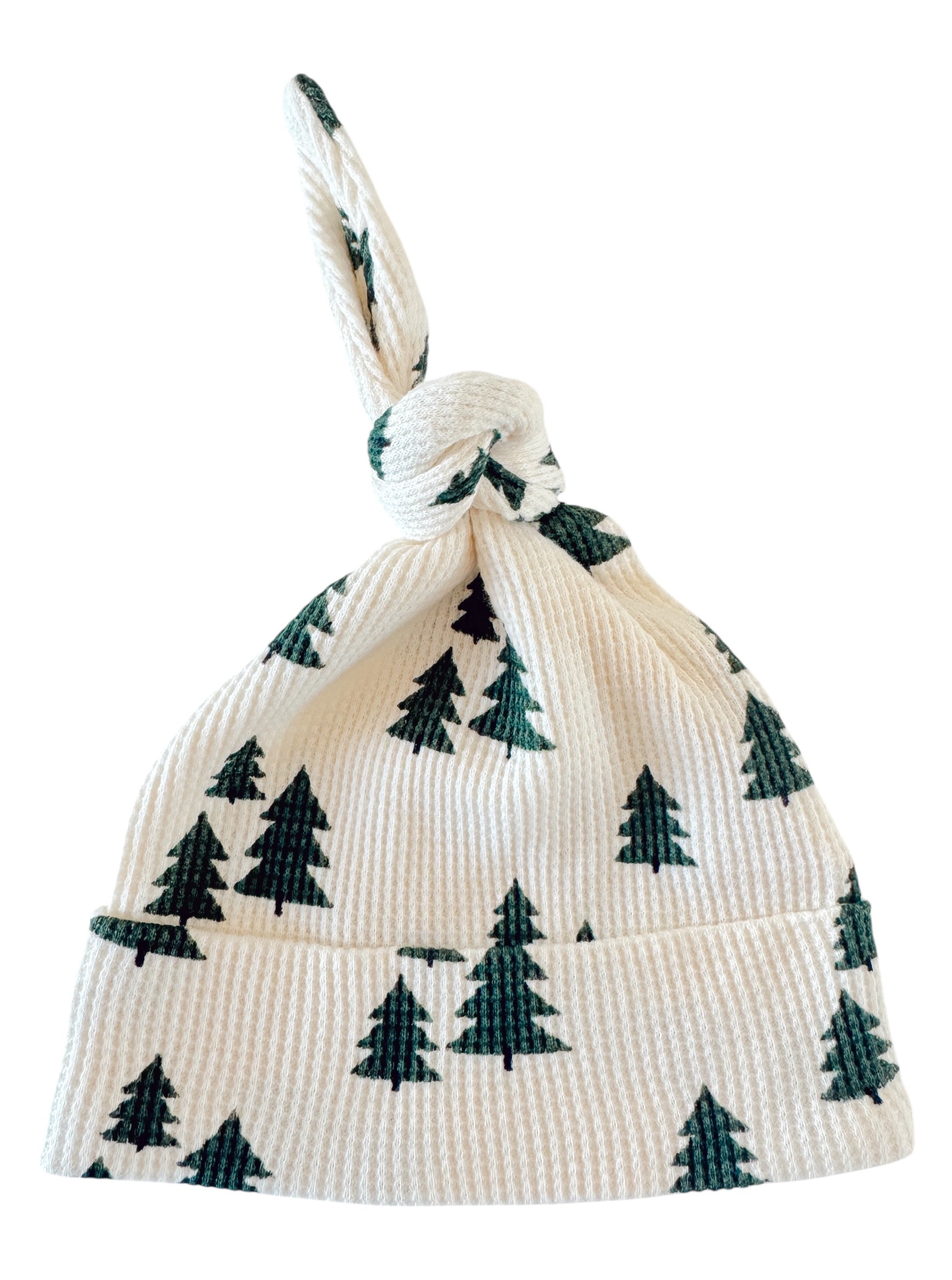 Knotted baby hat with green tree patterns on a white background, ideal for winter outings.