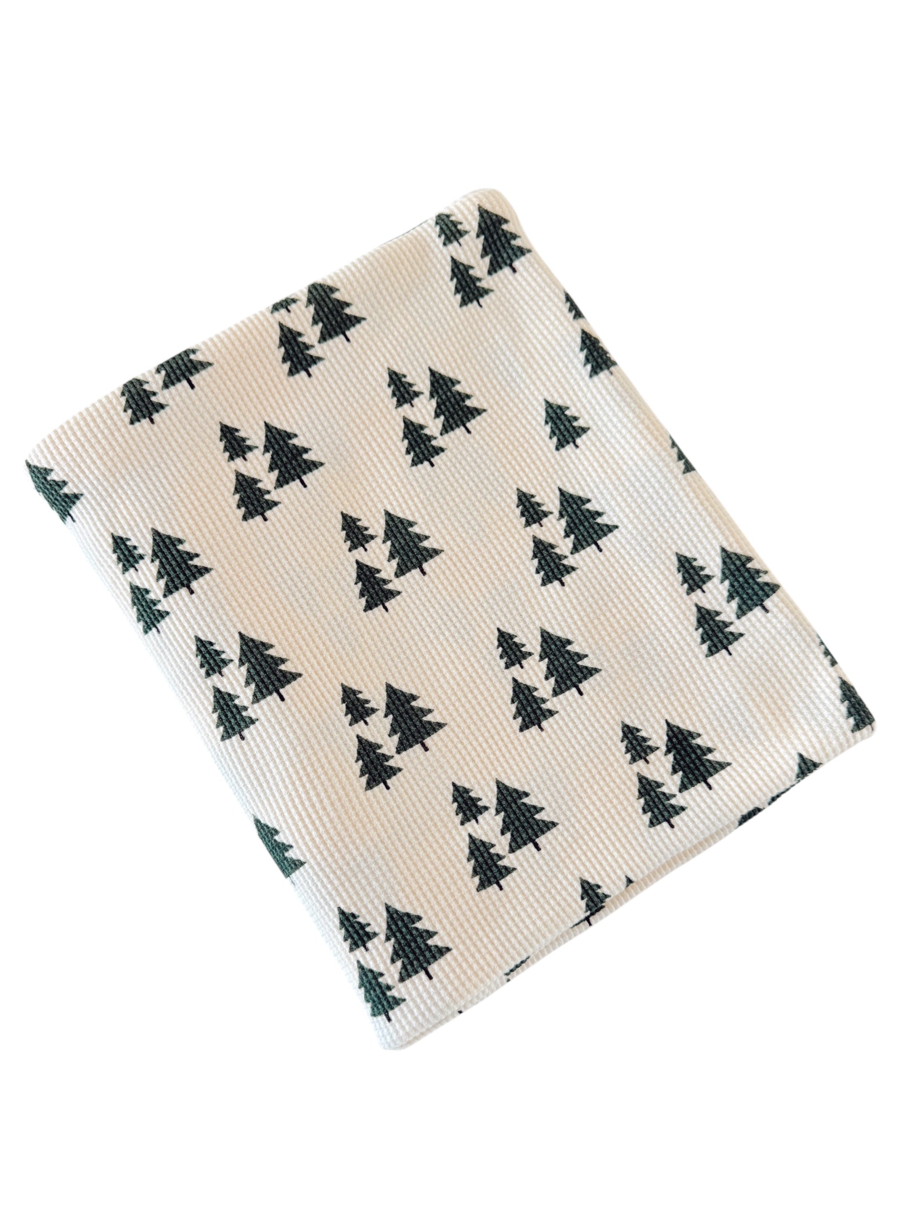 Cream fabric with green pine tree print, folded neatly. Ideal for seasonal decor or crafting projects.