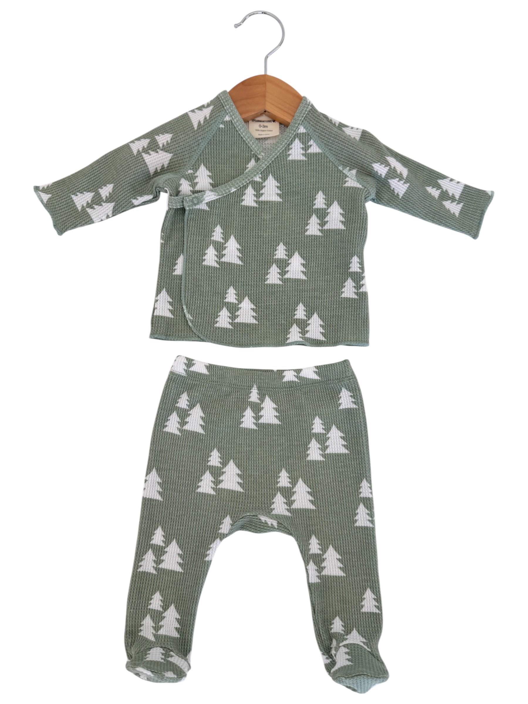 Green baby outfit with long-sleeve top and pants, featuring white tree patterns on a textured fabric.