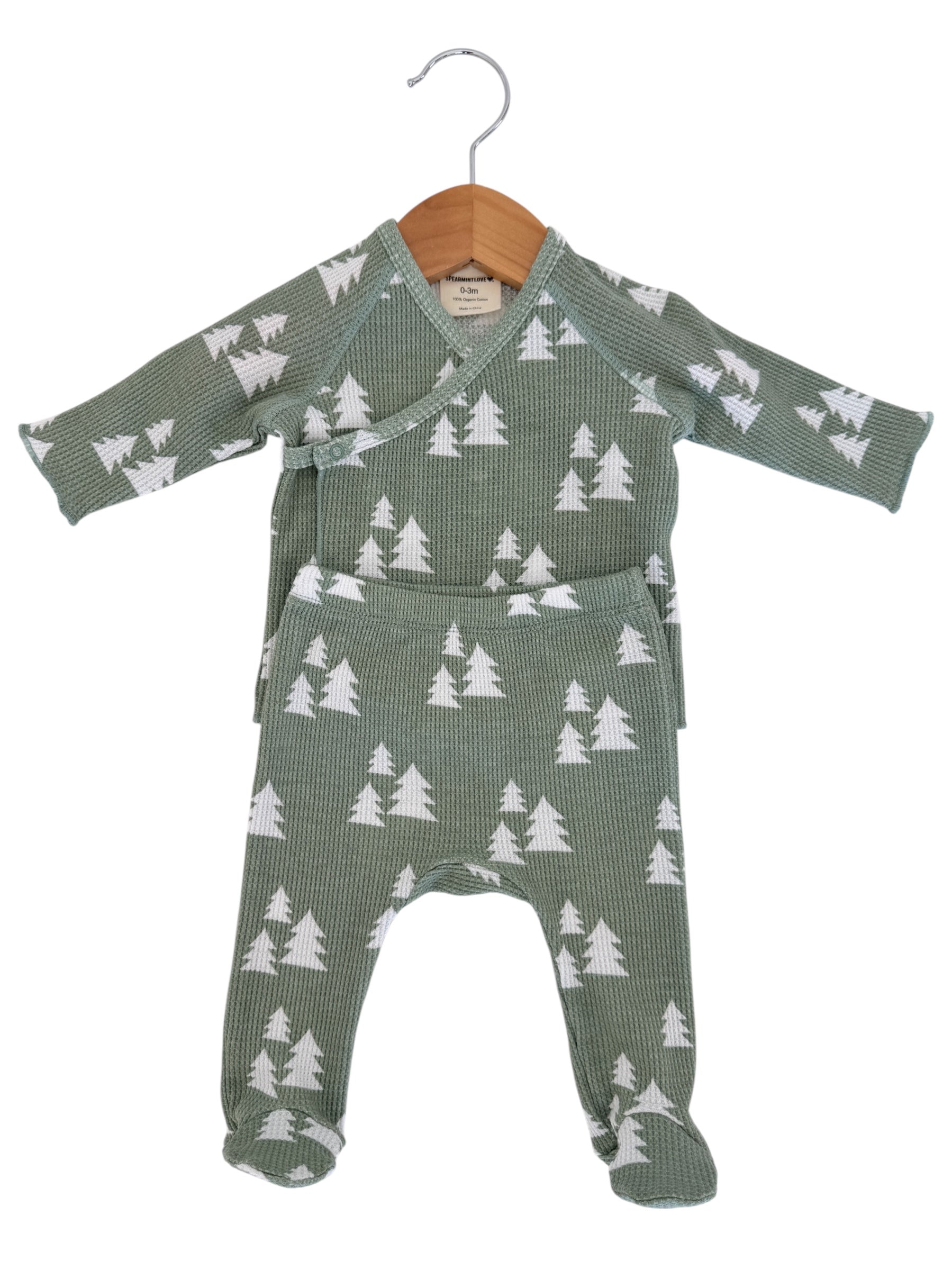 Green pajama set for infants with white tree patterns, displayed on a wooden hanger. Suitable for ages 0-3 months.