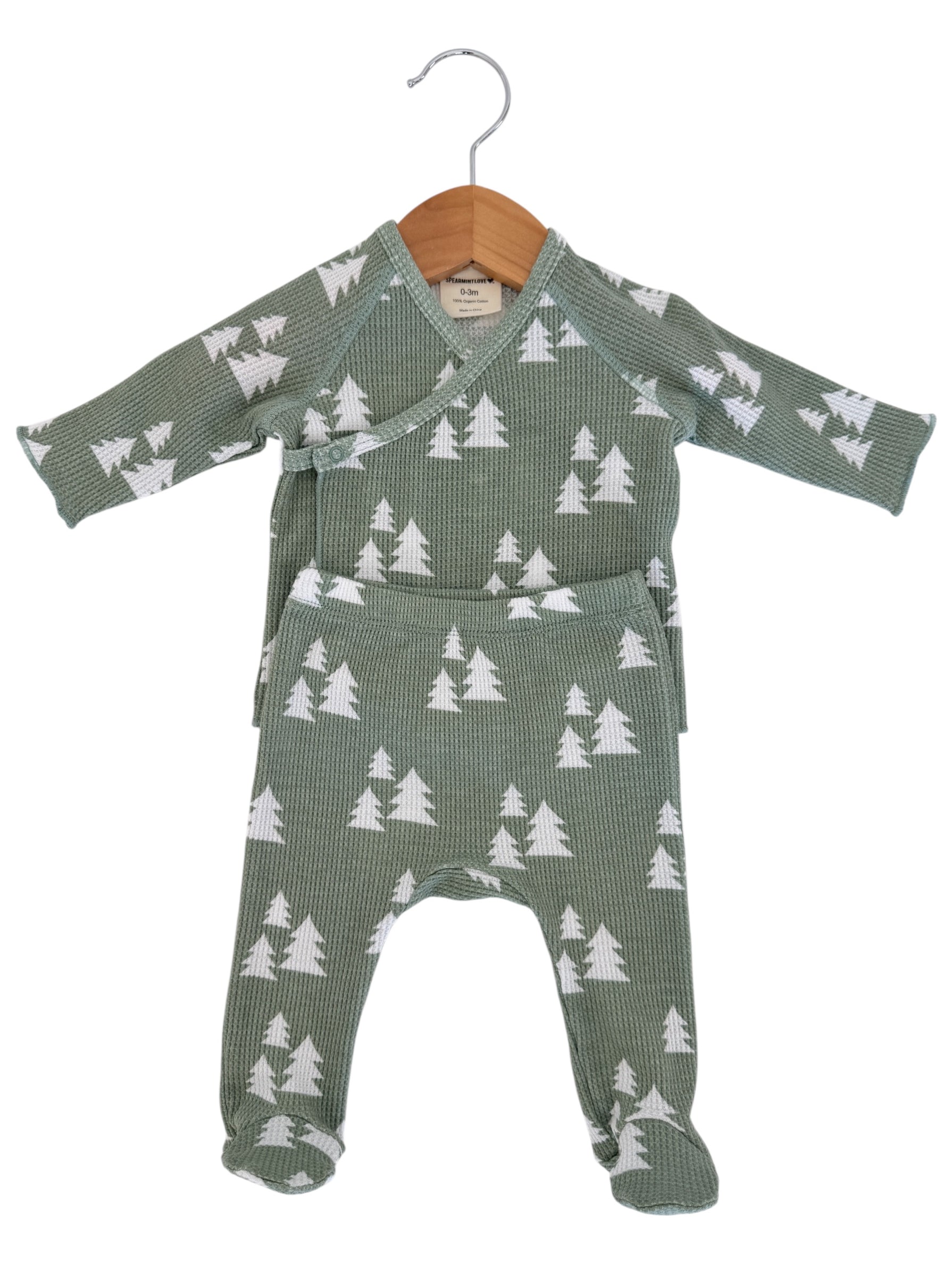 Green pajama set for infants with white tree patterns, displayed on a wooden hanger. Suitable for ages 0-3 months.
