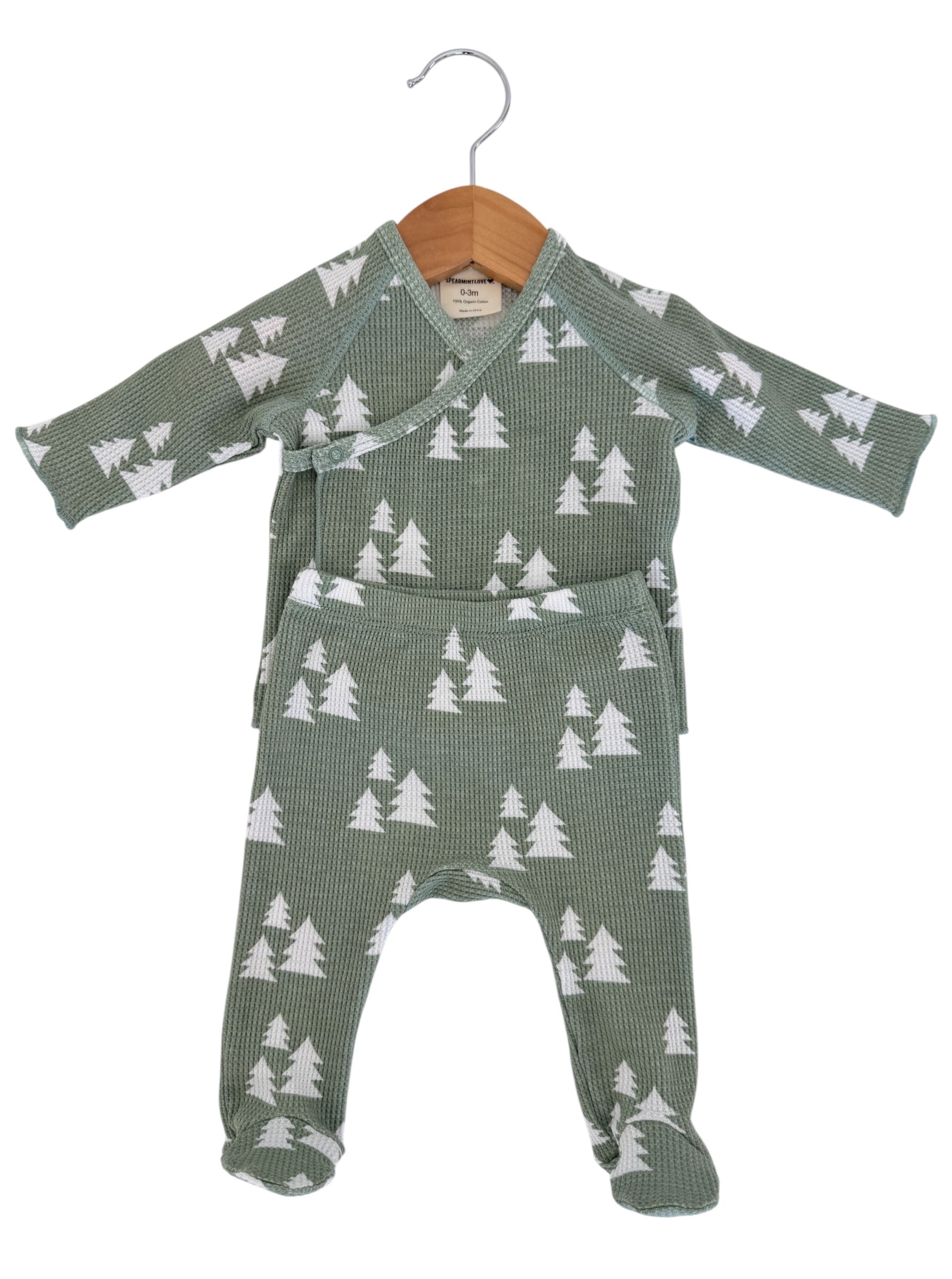 Green pajama set for infants with white tree patterns, displayed on a wooden hanger. Suitable for ages 0-3 months.
