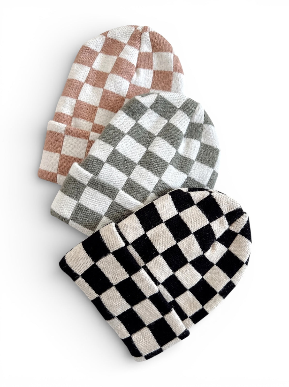 Three beanies in checkered patterns: pink, green, and black, stacked on a white background.