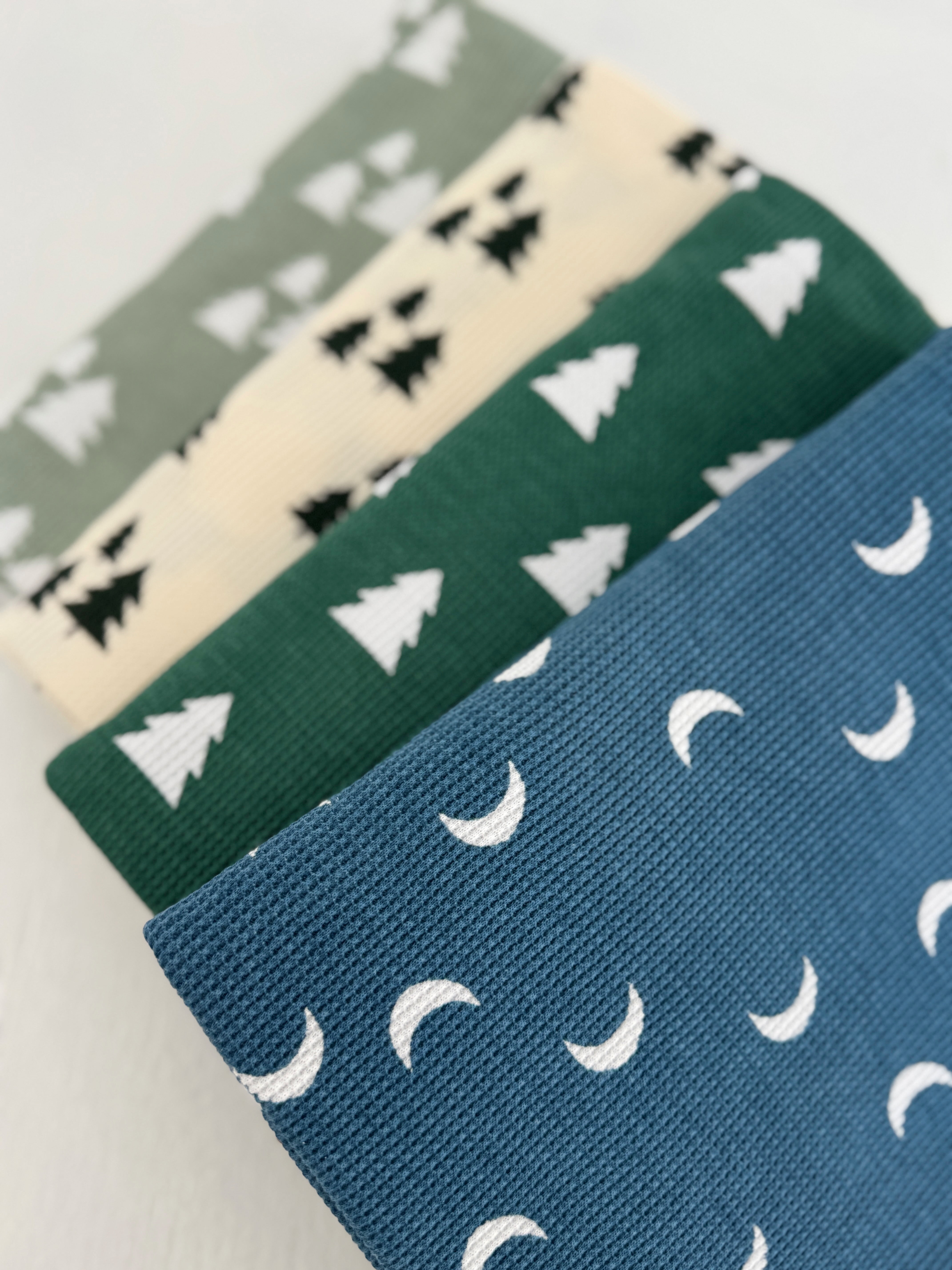 Four fabrics featuring tree and moon patterns in green, blue, cream, and black colors.