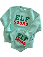 Matching mint green sweaters for kids and adults with "ELF SQUAD" in colorful letters.