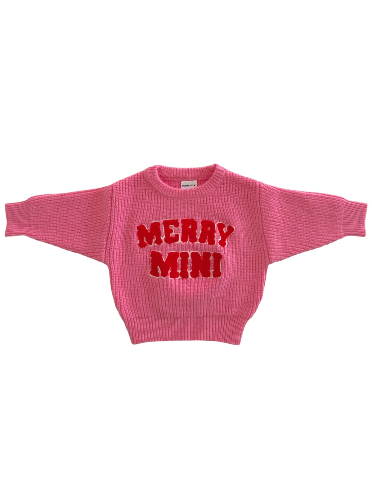 Pink sweater with "MERRY MINI" in bold red letters on the front, featuring a ribbed texture and wide sleeves.