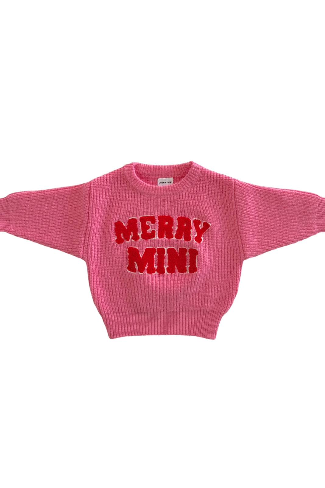 Pink sweater with "MERRY MINI" in bold red letters on the front, featuring a ribbed texture and wide sleeves.